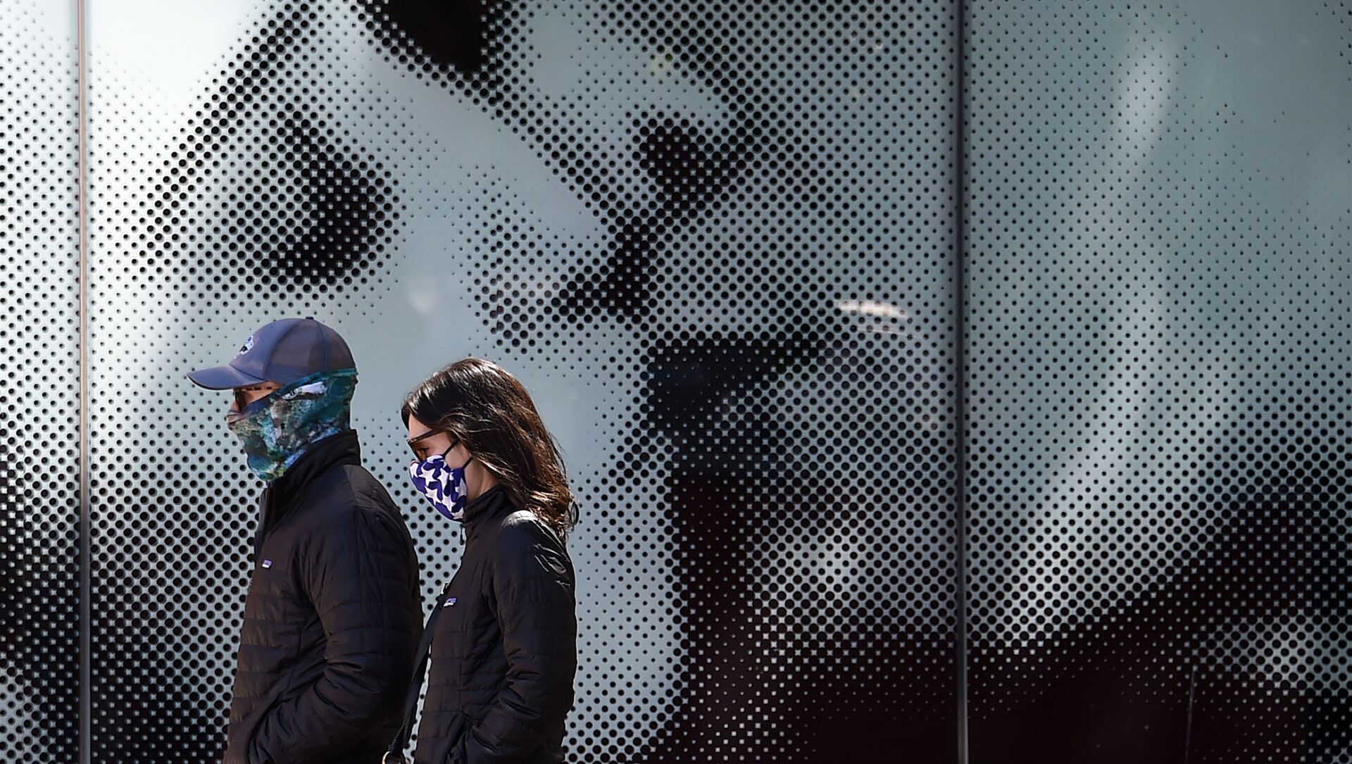 ثنائي يرتدي كمامات واقية يسيران على خلفية لوحة إعلانية لدار السينما، وسط جائحة فيروس كورونا في واشنطن العاصمة، في 22 أبريل 2020. - سبوتنيك عربي, 1920, 08.06.2021