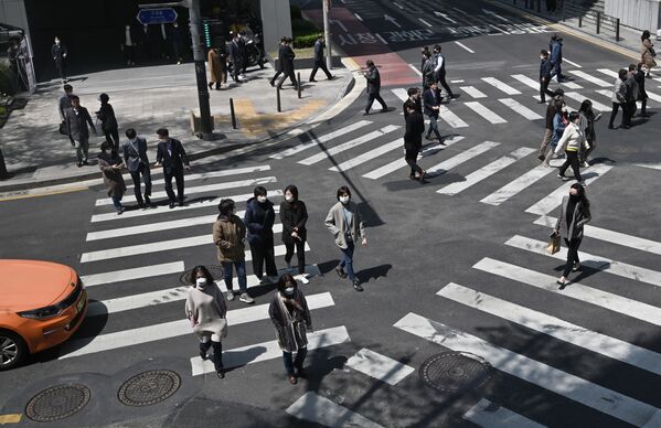 أشخاص مقنعون يعبرون مفترق طرق عند معابر المشاة في سئول، كوريا الجنوبية  23 أبريل 2020 - سبوتنيك عربي