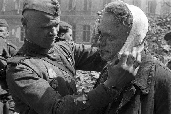 صور من أرشيف الحرب الوطنية العظمى (1941 - 1945) - جندي سوفيتي يقوم بتضميد جراح مواطن من برلين، 1945 - سبوتنيك عربي