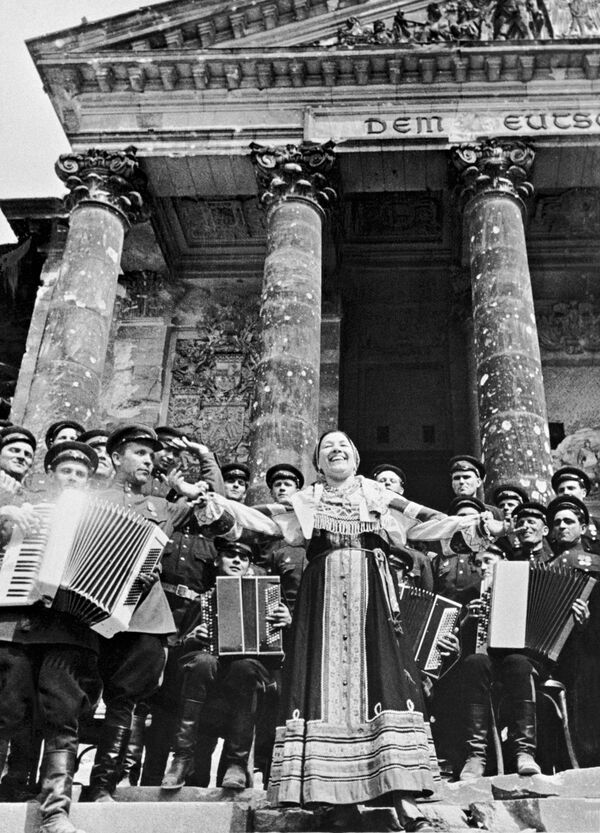 صور من أرشيف الحرب الوطنية العظمى (1941 - 1945) - الفنانة الشعبية السوفيتية ليديا روسلانوفا تغني للجنود السوفيتيين أمام مبنى الرايخستاغ في برلين، مايو/ أيار 1945 - سبوتنيك عربي