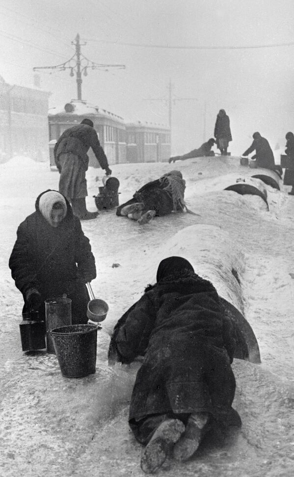 صور من أرشيف الحرب الوطنية العظمى (1941 - 1945) - سكان مدينة لينينغراد (سان بطرسبورغ) يقومون بتعبئة المياه من خط مكسور في أحد شوارع المدينة خلال شتاء قارس البرودة، 1 يناير/ كانون الثاني عام 1942 - سبوتنيك عربي