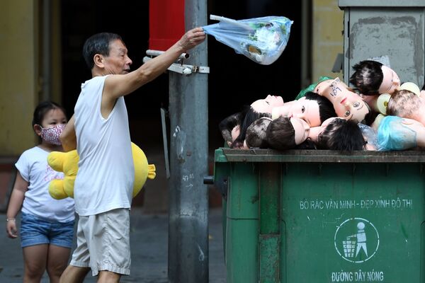  رجل يلقي القمامة في صندوق مليء برؤوس المانيكان في هانوي، فيتنام 7 مايو / أيار 202 - سبوتنيك عربي