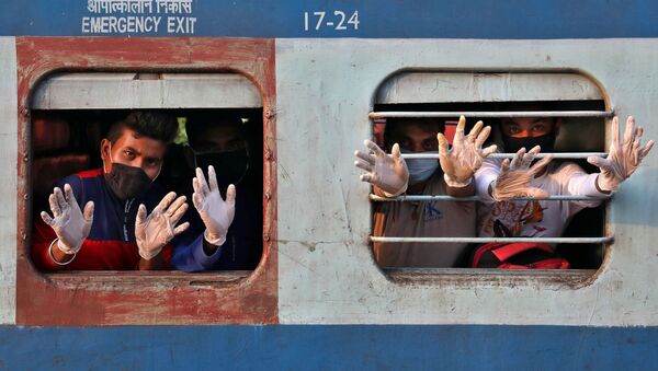 يلوح أشخاص يرتدون قفازات من القطار لدى وصولهم من ولاية تاميل نادو الجنوبية، وذلك بعد إعادة فتح محدود لخط السكك الحديدية في الهند بعد إغلاق لمدة سبعة أسابيع تقريبًا لإبطاء انتشار مرض (كوفيد-19)، في محطة سكة الحديد هوراه جانكشون على مشارف كلكتا، الهند  12 مايو 2020. - سبوتنيك عربي