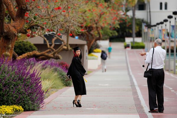 متخرجة من جامعة سان دييغو الحكومية، تستعد لإلتقاط صورة للذكرى بتخرجها أمام الحرم الجامعي أثناء تفشي مرض فيروس كورونا (كوفيد-19) في سان دييغو، كاليفورنيا، الولايات المتحدة، 13 مايو 2020. - سبوتنيك عربي
