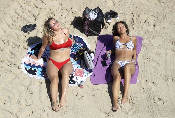 فتاتان على شاطئ كوليركوتس، في أحد أحر الأيام في إنجلترا  20 مايو 2020  على الرغم من الاجراءات الاحترازية المفروضة بسبب جائحة كورونا وعدم السماح بالسباحة في بريطانيا. - سبوتنيك عربي