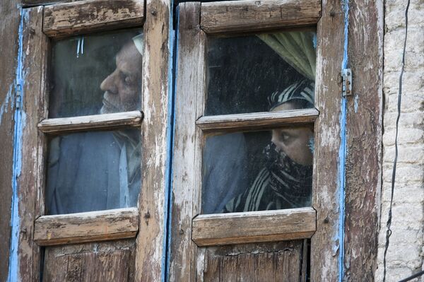 سكان يراقبون من نافذتهم في منطقة بالقرب من موقع الاشتباكات بالأسلحة النارية بين مسلحين مشتبه بهم والقوات الحكومية في سريناغار، 19 مايو 2020. - سبوتنيك عربي