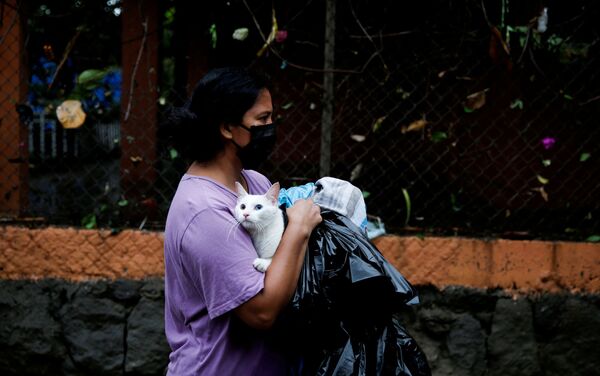 امرأة ترتدي كمامة حاملة قطها أثناء فياضانات سببها إعصار أماندا في مدينة إلوبانغو، سلفادور 31 مايو 2020 - سبوتنيك عربي