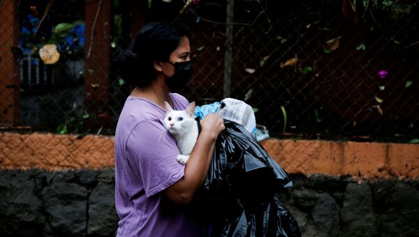 امرأة ترتدي كمامة حاملة قطها أثناء فياضانات سببها إعصار أماندا في مدينة إلوبانغو، سلفادور 31 مايو 2020 - سبوتنيك عربي