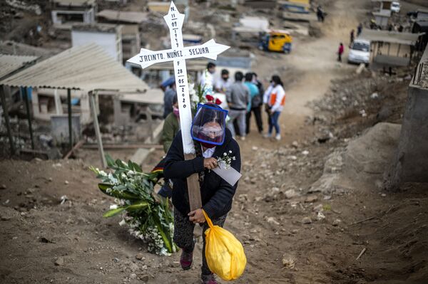 أحد أقرباء ضحايا كوفيد-19 يحمل صلبيا في مقبرة في ضواحي مدينة ليما، بيرو 30 مايو 2020 - سبوتنيك عربي