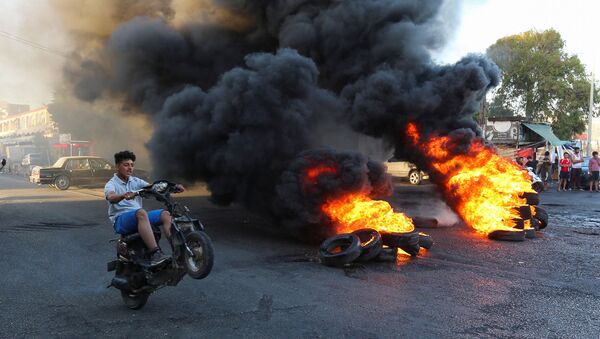 شاب يركب دراجته النارية بالقرب من اطارات مشتعلة خلال اعتصام احتجاجا على تراجع سعر الجنيه وتزايد الصعوبات الاقتصادية في الغازية - سبوتنيك عربي