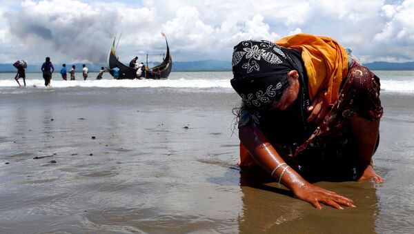 لاجئة من الروهينغا المنهكة تلمس الشاطئ بعد عبورها الحدود بين بنغلاديش وميانمار عن طريق القوارب عبر خليج البنغال في شاه بورير دويب في بنغلاديش - سبوتنيك عربي