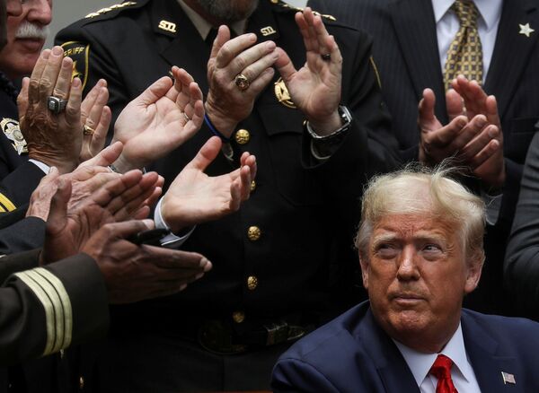 الرئيس الأمريكي دونالد ترامب وسط التصفيق بعد مراسم التوقيع على أمر تنفيذي فيما يخص الإصلاح بالشرطة، في فناء البيت الأبيض في واشنطن، الولايات المتحدة، 16 يونيو  2020 - سبوتنيك عربي
