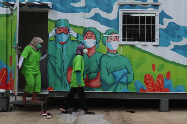 العاملون في القطاع الصحي يخرجون من مختبر متنقل قبل تحليل العينات التي تم جمعها خلال اختبارات عامة لفيروس كورونا في جاكرتا، إندونيسيا، 18 يونيو 2020 - سبوتنيك عربي