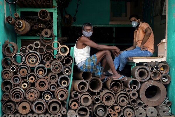 عمال يرتدون كمامات داخل متجر لبيع أنابيب الحديد في سوق حديدية بالجملة، بعد أن خففت السلطات المحلية القيود المشددة المفروضة لمنع انتشار المرض الفيروسي (كوفيد-19)  في كلكتا، الهند، 15 يونيو / حزيران 2020. - سبوتنيك عربي