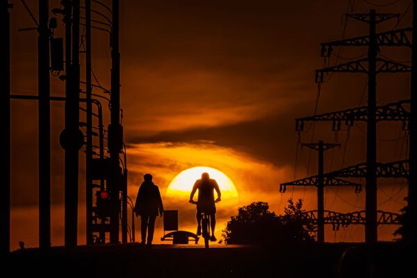 رجل يركب دراجة هوائية في حديقة على خلفية غروب الشمس، حيث دخلت موسكو المرحلة الثانية من رفع القيود المفروضة بسبب كورونا، 14 يونيو 2020 - سبوتنيك عربي