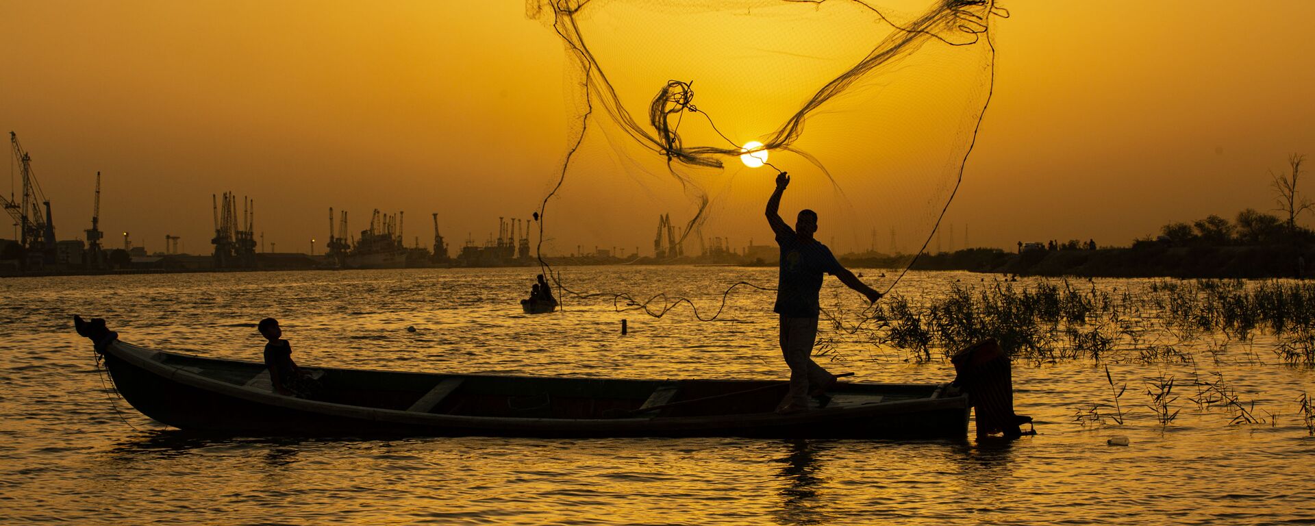 صياد السمك يلقي بشبكته عند الغروب في مياه نهر شط العرب في مدينة البصرة، العراق 12 يونيو 2020 - سبوتنيك عربي, 1920, 12.03.2021