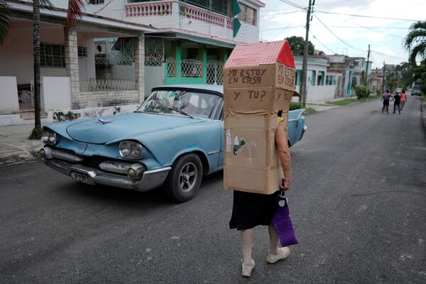 ممرضة متقاعدة، فيديا روخاس (82 عاما)، ترتدي مجسما من الكرتون على شكل منزل، لحماية نفسها من المرض الفيروسي (كوفيد-19) في هافانا، كوبا ، 16 يونيو / 2020. - سبوتنيك عربي