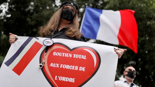 أحد مؤيدي قوات الشرطة ترتدي قناع الوجه الواقي وتحمل لافتة وهي تتظاهر أمام مقر الشرطة الفرنسية في باريس - سبوتنيك عربي