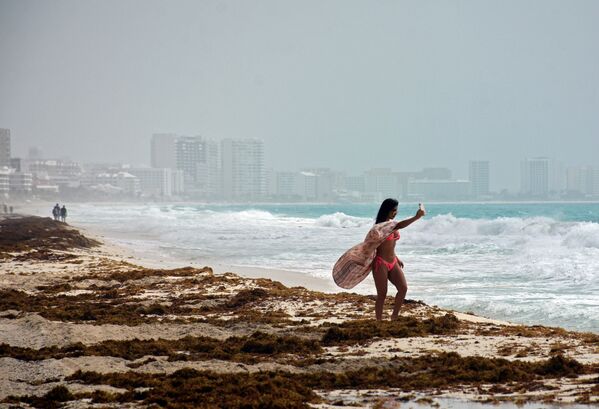 فتاة تلتقط صورة سيلفي على خلفية سحابة رملية على شاطئ المكسيك، 25 يونيو 2020 - سبوتنيك عربي