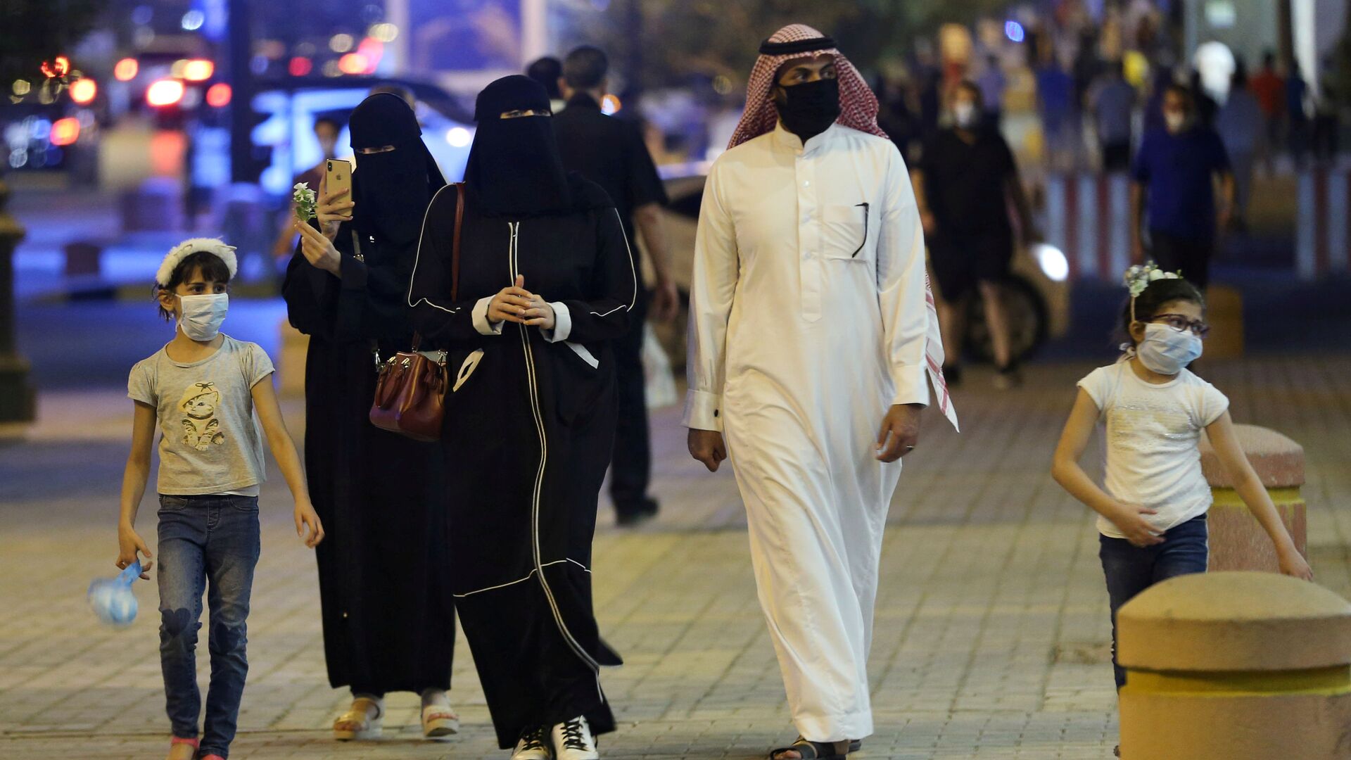 عائلة سعودية ترتدي أقنعة واقية للوجه تسير في شارع التحلية بعد أن خففت الحكومة قيود الإغلاق بعد تفشي مرض فيروس كورونا في الرياض - سبوتنيك عربي, 1920, 10.07.2021