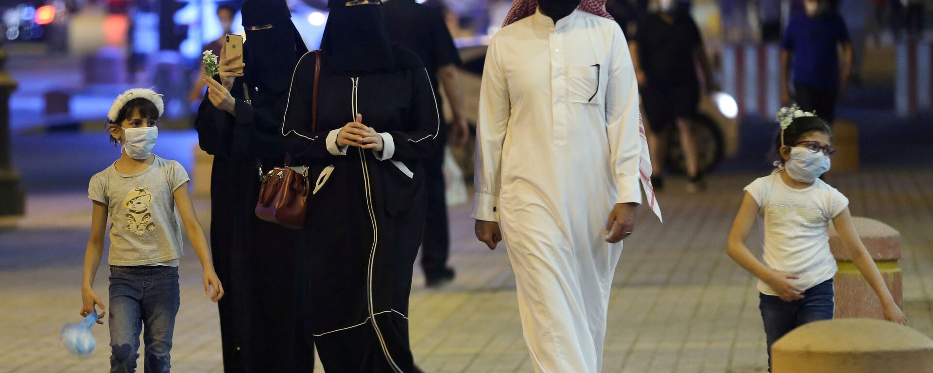 عائلة سعودية ترتدي أقنعة واقية للوجه تسير في شارع التحلية بعد أن خففت الحكومة قيود الإغلاق بعد تفشي مرض فيروس كورونا في الرياض - سبوتنيك عربي, 1920, 18.05.2021