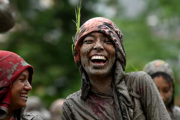 امرأة تبتسم في حقل أرز خلال يوم الأرز الوطني، الذي يمثل بداية موسم زراعة الأرز السنوي، في قرية توكا على مشارف كاتماندو في 29 يونيو 2020. - سبوتنيك عربي