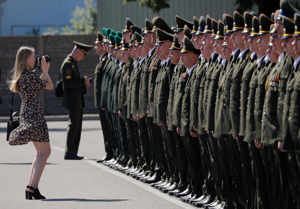 امرأة تلتقط صورًا للخريجين أثناء مراسم توزيع الدبلوم في الأكاديمية العسكرية في بيلاروسيا، وسط تفشي مرض فيروس التاجي كوفيد-19 في مينسك، بيلاروسيا، 27 يونيو 2020. - سبوتنيك عربي